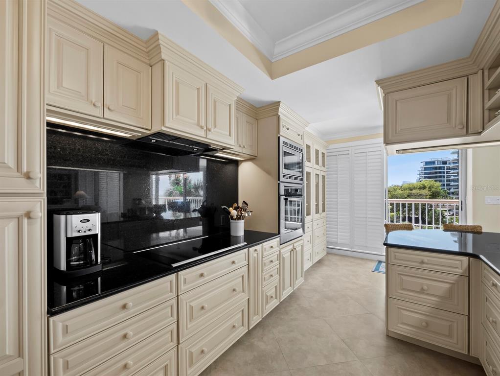 455 Longboat Club Road, Unit 402 Longboat Key, FL 34228 - Photo 12 of 48 a kitchen with granite countertop white cabinets and window