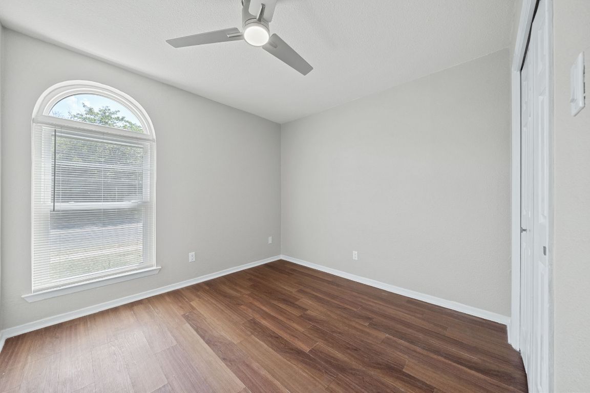 1810 Mearns Meadow Boulevard, Unit B Austin, TX 78758 - Photo 11 of 21 an empty room with wooden floor fan and windows