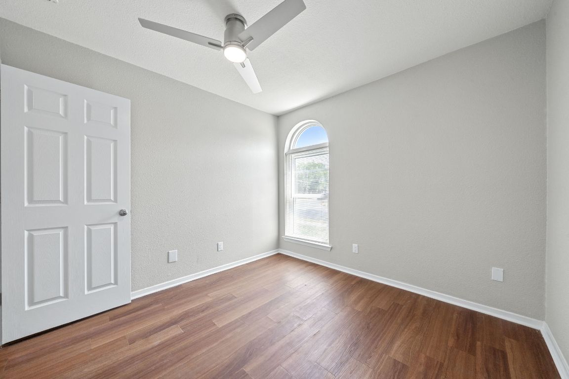 1810 Mearns Meadow Boulevard, Unit B Austin, TX 78758 - Photo 12 of 21 an empty room with wooden floor fan and windows