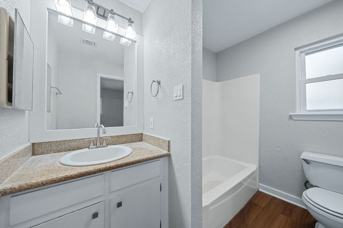 1810 Mearns Meadow Boulevard, Unit B Austin, TX 78758 - Photo 13 of 21 a bathroom with a granite countertop sink a toilet and shower