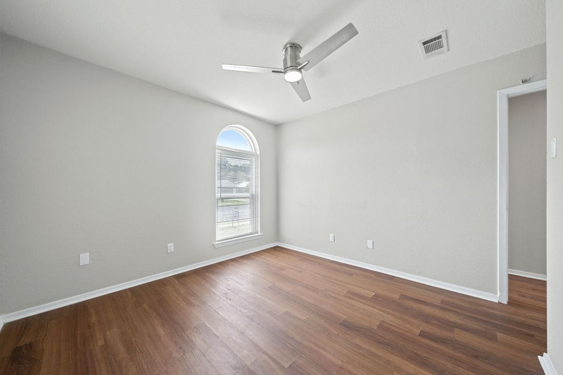 1810 Mearns Meadow Boulevard, Unit B Austin, TX 78758 - Photo 17 of 21 an empty room with wooden floor fan and windows