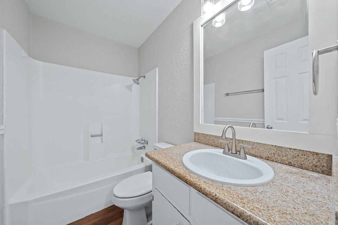 1810 Mearns Meadow Boulevard, Unit B Austin, TX 78758 - Photo 19 of 21 a bathroom with a granite countertop sink a toilet and a mirror