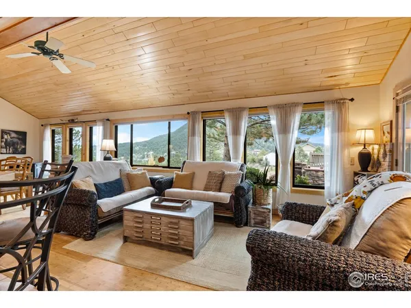 a living room with furniture large windows and wooden floor