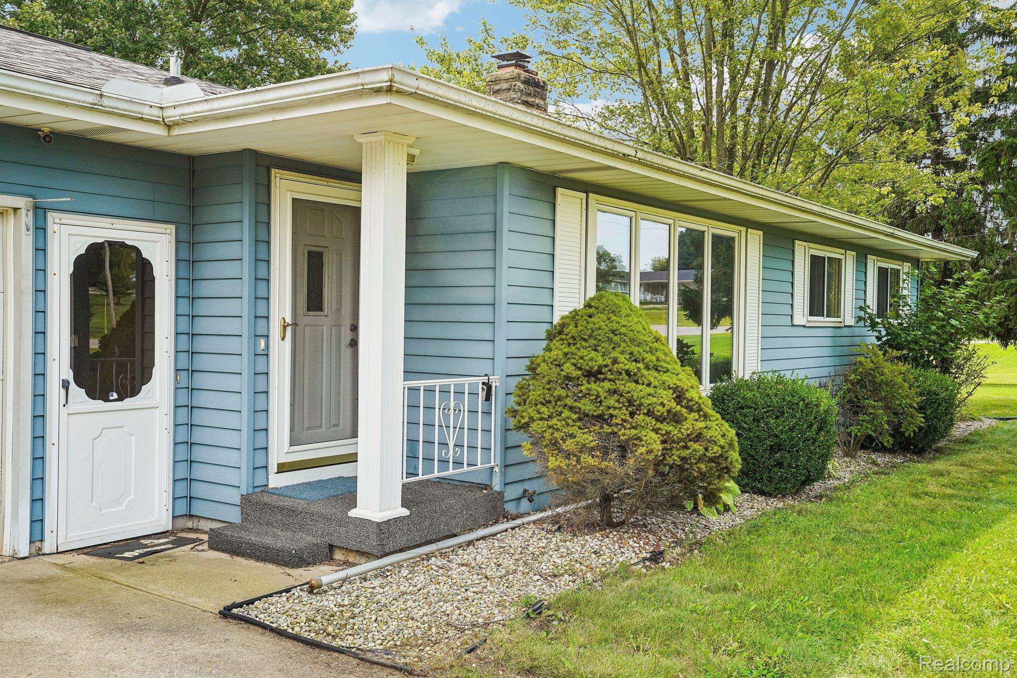 3981 South State Road Durand, MI 48429 - Photo 3 of 33 Blue siding exterior with white trim, a covered entry, and a gravel landscape bed