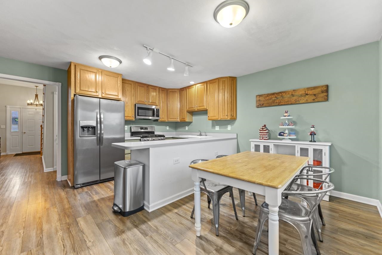 2108 Lake Summerset Road Lake Summerset, IL 61019 - Photo 17 of 53 a kitchen with granite countertop a refrigerator a stove a sink dishwasher a dining table and chairs with wooden floor