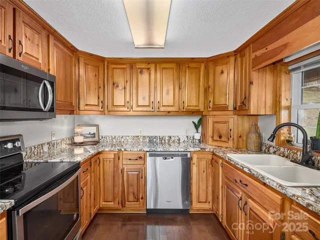 a kitchen with stainless steel appliances granite countertop a sink stove and cabinets
