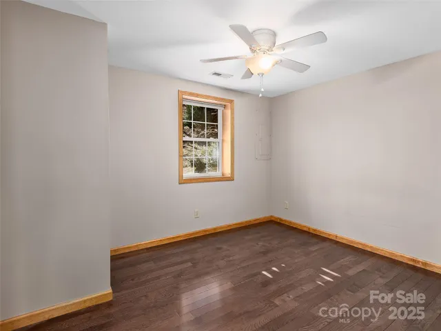 an empty room with wooden floor and ceiling fan
