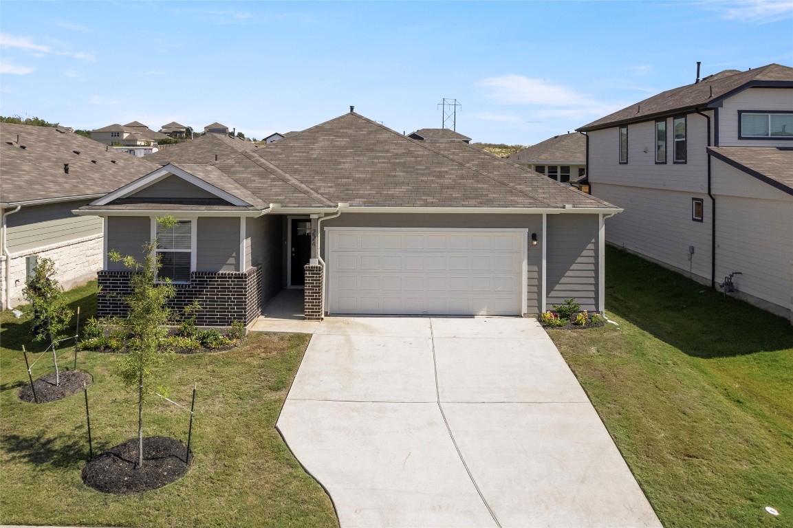 224 Kickapoo Lane Kyle, TX 78640 - Photo 1 of 31 View of front of property featuring concrete driveway, an attached garage, roof with shingles, and a front lawn