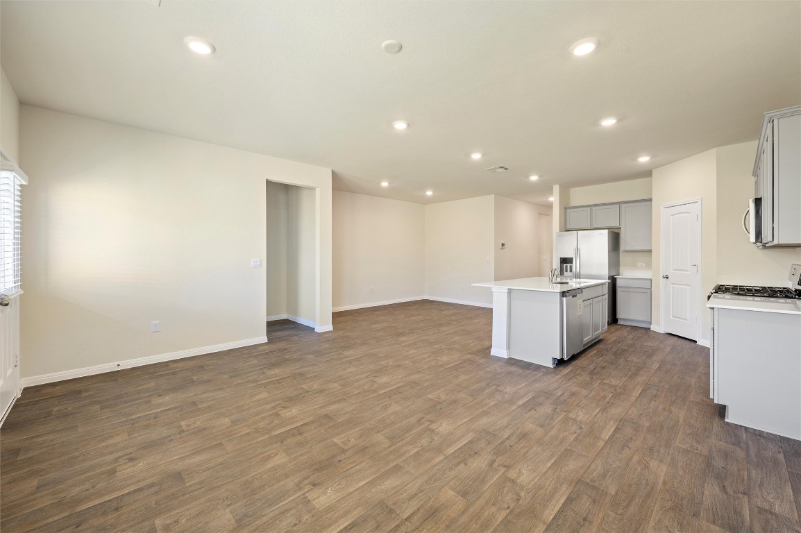 224 Kickapoo Lane Kyle, TX 78640 - Photo 30 of 31 Kitchen featuring open floor plan, dark wood finished floors, gray cabinetry, an island with sink, and appliances with stainless steel finishes