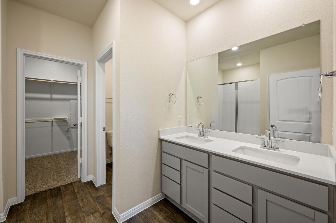 224 Kickapoo Lane Kyle, TX 78640 - Photo 13 of 31 Bathroom featuring a shower stall, a spacious closet, double vanity, dark wood-style floors, and recessed lighting