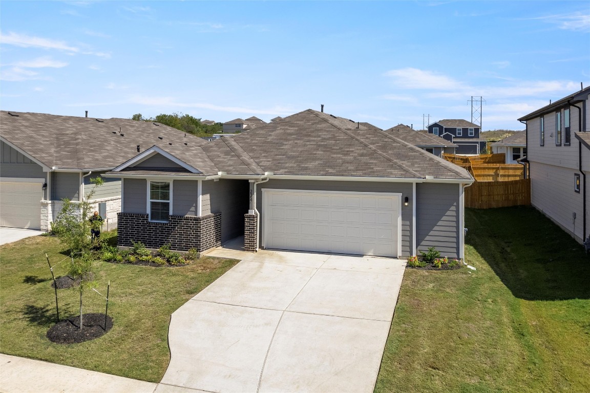 224 Kickapoo Lane Kyle, TX 78640 - Photo 2 of 31 View of front facade featuring concrete driveway, roof with shingles, an attached garage, and a residential view