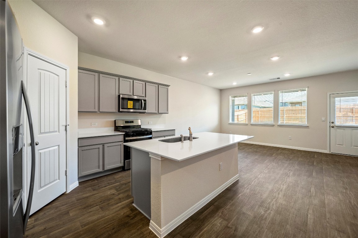 224 Kickapoo Lane Kyle, TX 78640 - Photo 6 of 31 Kitchen featuring gray cabinetry, appliances with stainless steel finishes, an island with sink, dark wood finished floors, and recessed lighting