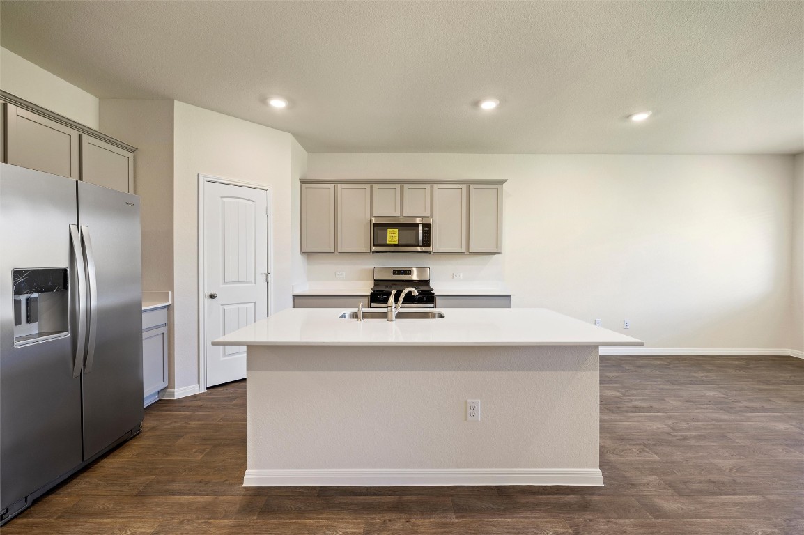 224 Kickapoo Lane Kyle, TX 78640 - Photo 7 of 31 Kitchen with appliances with stainless steel finishes, gray cabinetry, a center island with sink, dark wood-style flooring, and recessed lighting