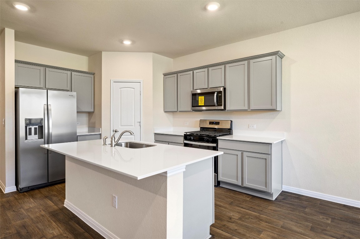 224 Kickapoo Lane Kyle, TX 78640 - Photo 8 of 31 Kitchen with gray cabinetry, stainless steel appliances, an island with sink, dark wood-type flooring, and recessed lighting