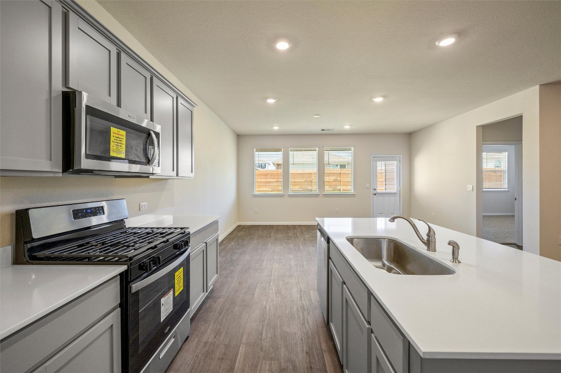 224 Kickapoo Lane Kyle, TX 78640 - Photo 10 of 31 Kitchen featuring gray cabinets, appliances with stainless steel finishes, a center island with sink, dark wood finished floors, and recessed lighting