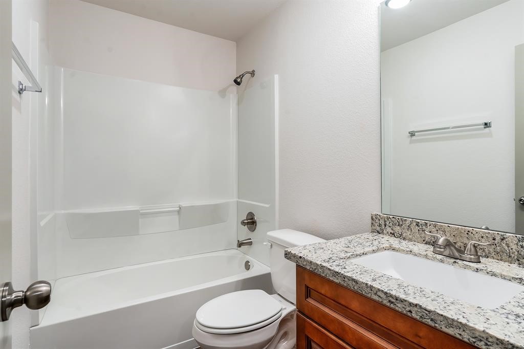 910 Shady Lane, Unit B Conroe, TX 77301 - Photo 17 of 18 a bathroom with a granite countertop bathtub shower sink vanity mirror and toilet