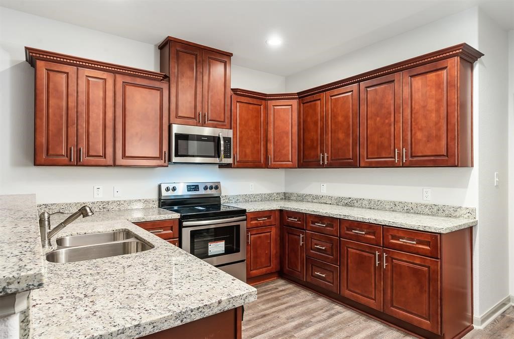 910 Shady Lane, Unit B Conroe, TX 77301 - Photo 5 of 18 a kitchen with stainless steel appliances granite countertop wooden cabinets a sink and dishwasher a oven with wooden cabinets