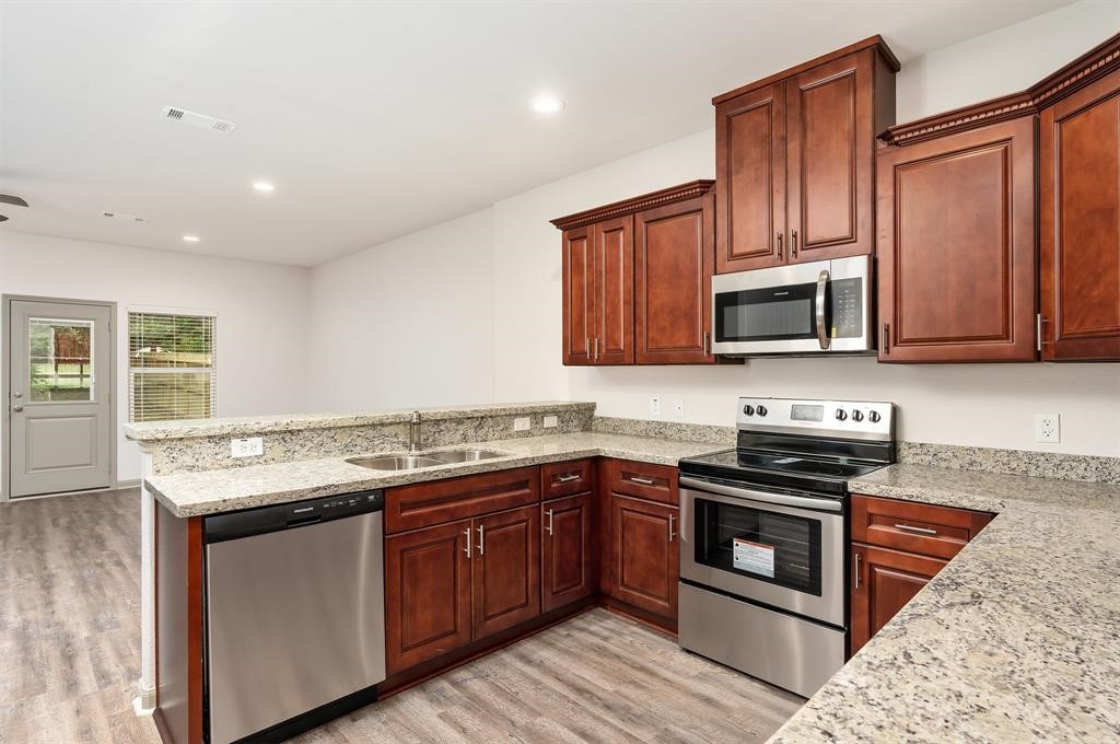 910 Shady Lane, Unit B Conroe, TX 77301 - Photo 6 of 18 a kitchen with stainless steel appliances granite countertop wooden cabinets stove top oven and sink