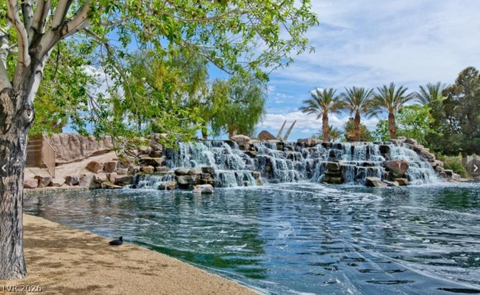 6405 North Raptor Court North Las Vegas, NV 89084 - Photo 64 of 66 A tranquil oasis featuring a cascading waterfall, serene pond, and lush surrounding greenery.