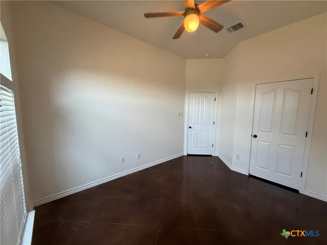 an empty room with a ceiling fan and a window