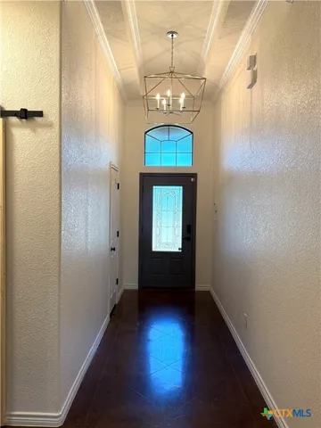 a view of a hallway with wooden floor and a chandelier