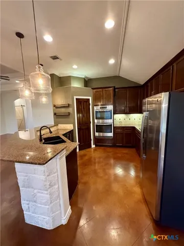 a kitchen with stainless steel appliances granite countertop a sink a stove and a refrigerator