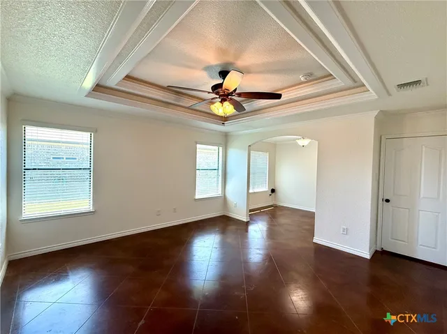 an empty room with wooden floor chandelier fan and windows