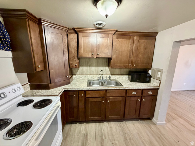 7 Foothill Boulevard Pocatello, ID 83204 - Photo 9 of 13 Kitchen featuring wood-finish cabinetry, light-toned countertops, a double basin sink, and wood-finish flooring