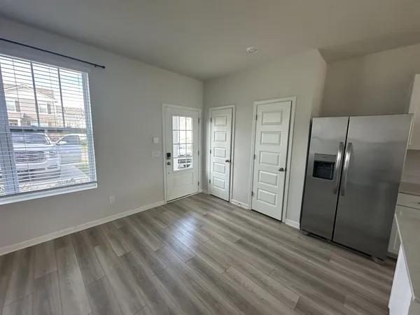 an empty room with wooden floor cabinet and windows