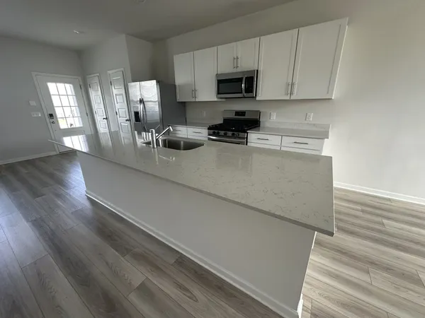 a kitchen with stainless steel appliances a sink a stove top oven a white counter space and cabinets