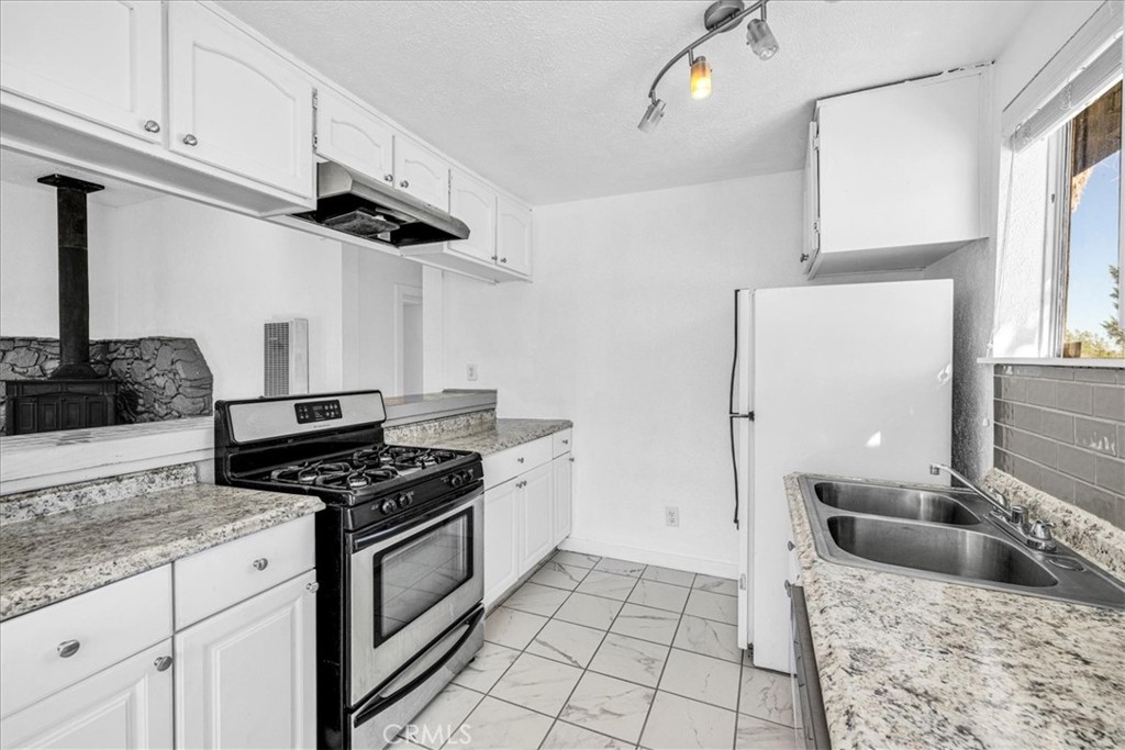 6686 Mojave Avenue Twentynine Palms, CA 92277 - Photo 14 of 41 a kitchen with granite countertop a sink a stove and refrigerator