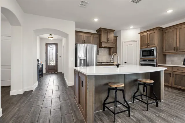 a kitchen with stainless steel appliances a dining table chairs refrigerator and sink