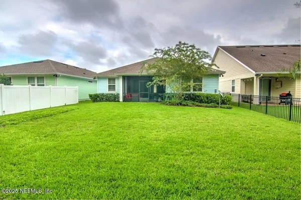 a view of a house next to a big yard and large trees