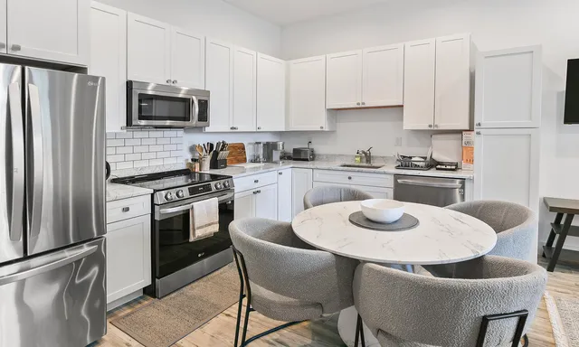 a kitchen with stainless steel appliances a stove a sink dishwasher a refrigerator and white cabinets