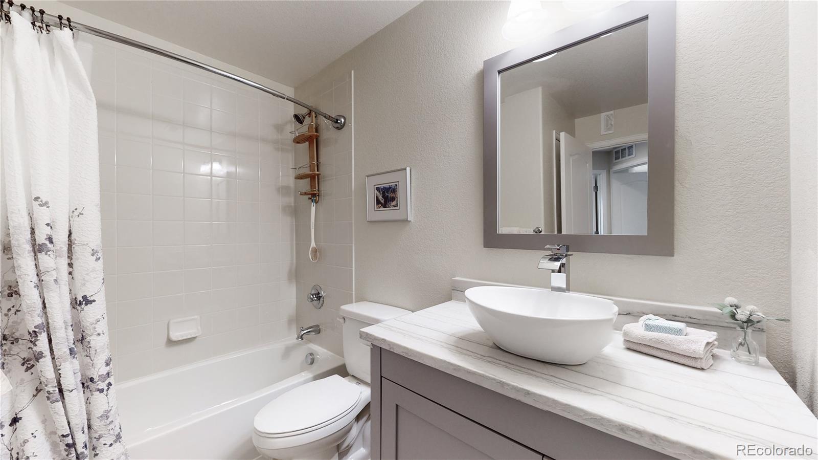 11331 Xavier Drive, Unit 103 Westminster, CO 80031 - Photo 12 of 30 a bathroom with a granite countertop sink toilet mirror and shower