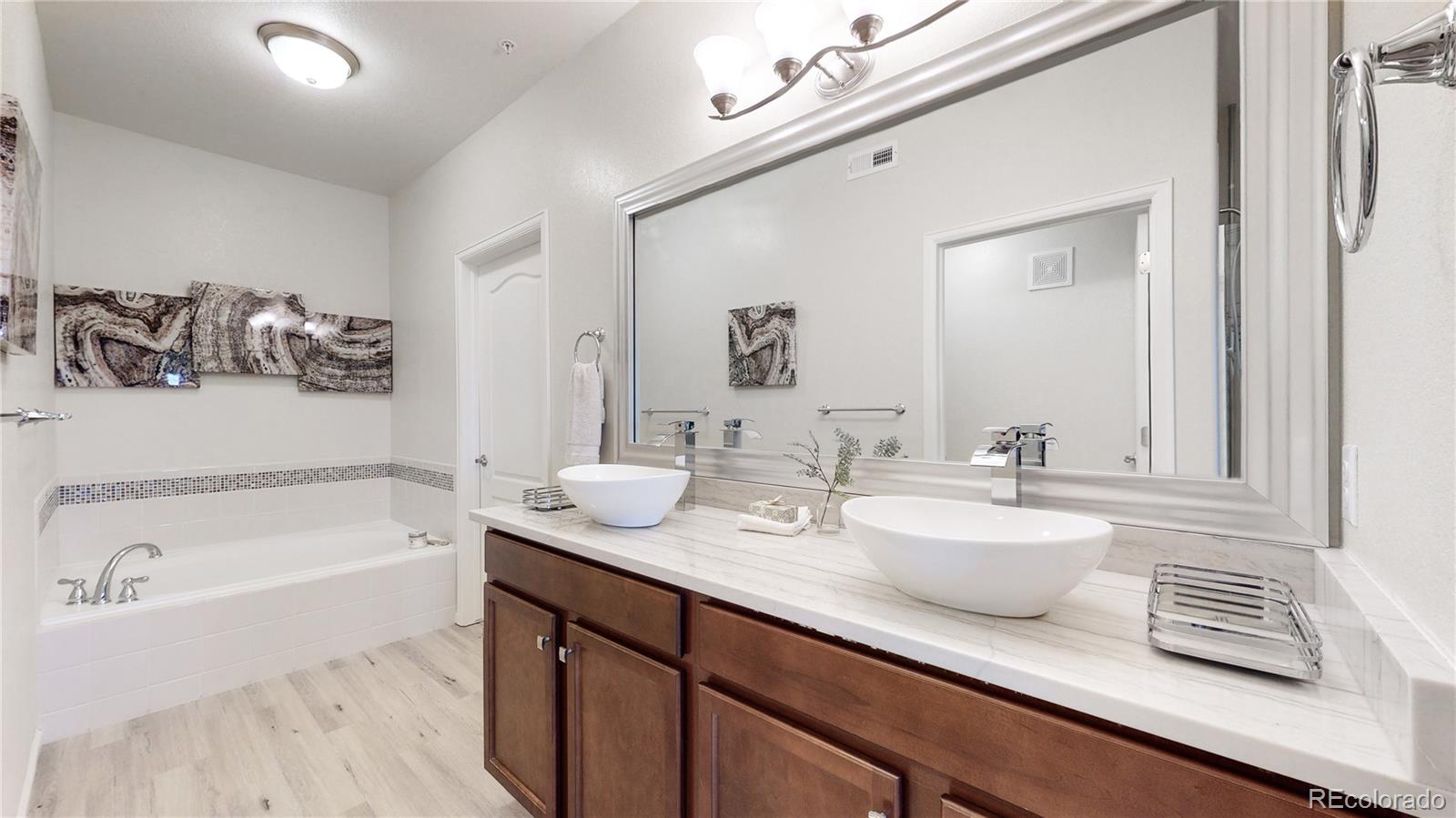 11331 Xavier Drive, Unit 103 Westminster, CO 80031 - Photo 9 of 30 a bathroom with a tub sink and mirror