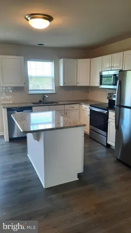 a kitchen with stainless steel appliances granite countertop a sink a microwave counter space and wooden floor