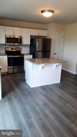 a kitchen with stainless steel appliances wooden cabinets and a wooden floor