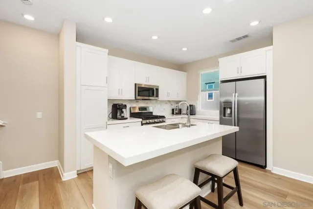 a kitchen with a refrigerator a stove microwave oven a sink and chairs