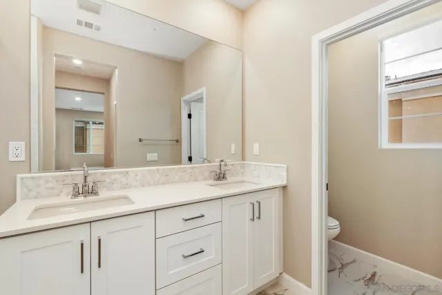a bathroom with a granite countertop sink a toilet and a mirror