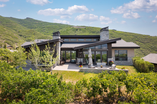 11547 Soaring Hawk Lane Hideout, UT 84036 - Photo 6 of 43 Modern mountain residence featuring a multi-level patio, stone accent walls, and a prominent chimney