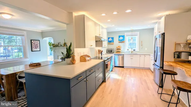 a large kitchen with stainless steel appliances a stove a sink dishwasher and a refrigerator with wooden floor