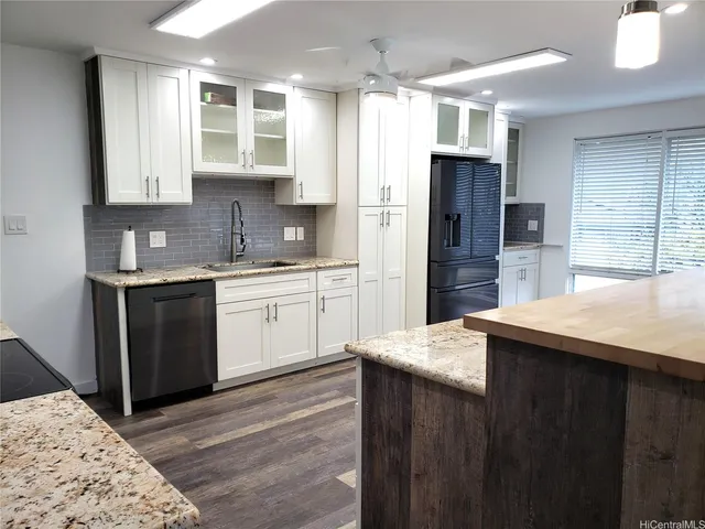 a kitchen with stainless steel appliances kitchen island granite countertop a sink refrigerator and cabinets