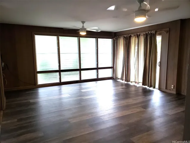 an empty room with wooden floor and large window