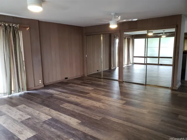 an empty room with wooden floor and windows with curtains