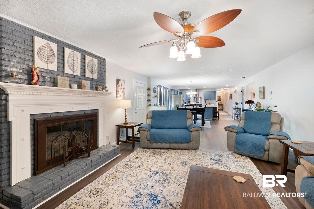 11901 Old Moffat Road Wilmer, AL 36587 - Photo 3 of 39 Living room with dark wood-type flooring, a ceiling fan, and a brick fireplace