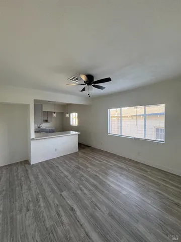a view of empty room with wooden floor and fan
