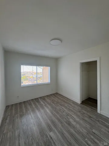 a view of an empty room with wooden floor and window