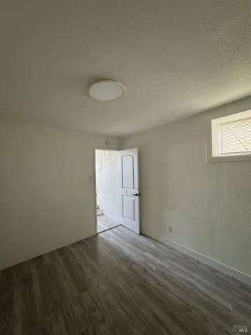 a view of an empty room with window and wooden floor