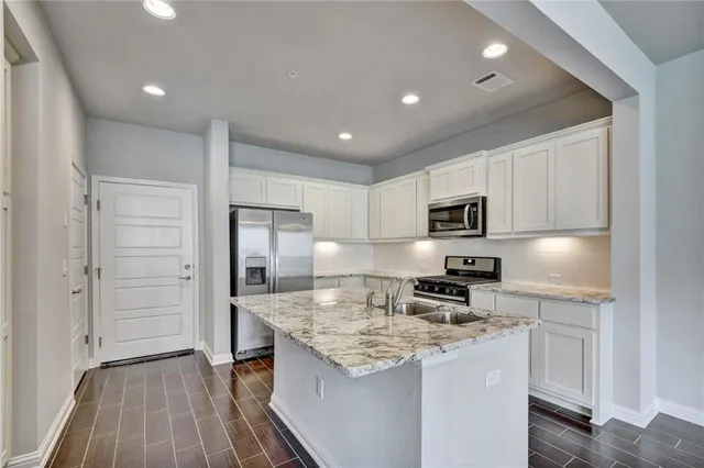 a kitchen with stainless steel appliances granite countertop a sink stove and refrigerator